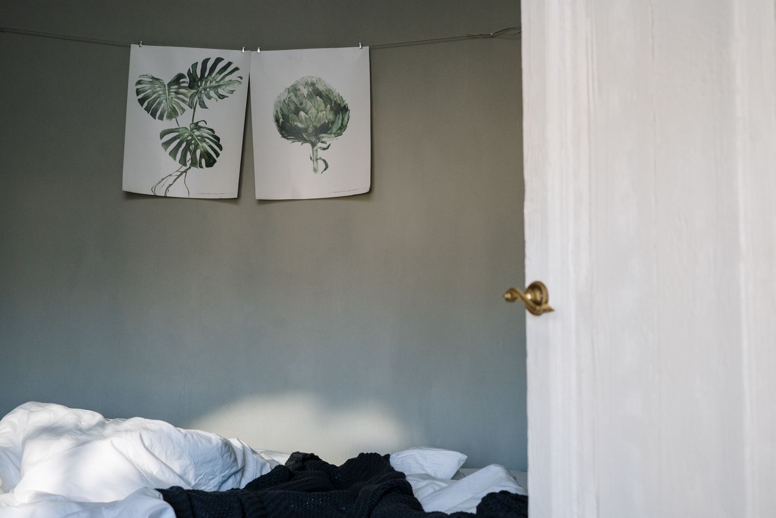 Bedroom with botanical leaf prints on a sage green wall