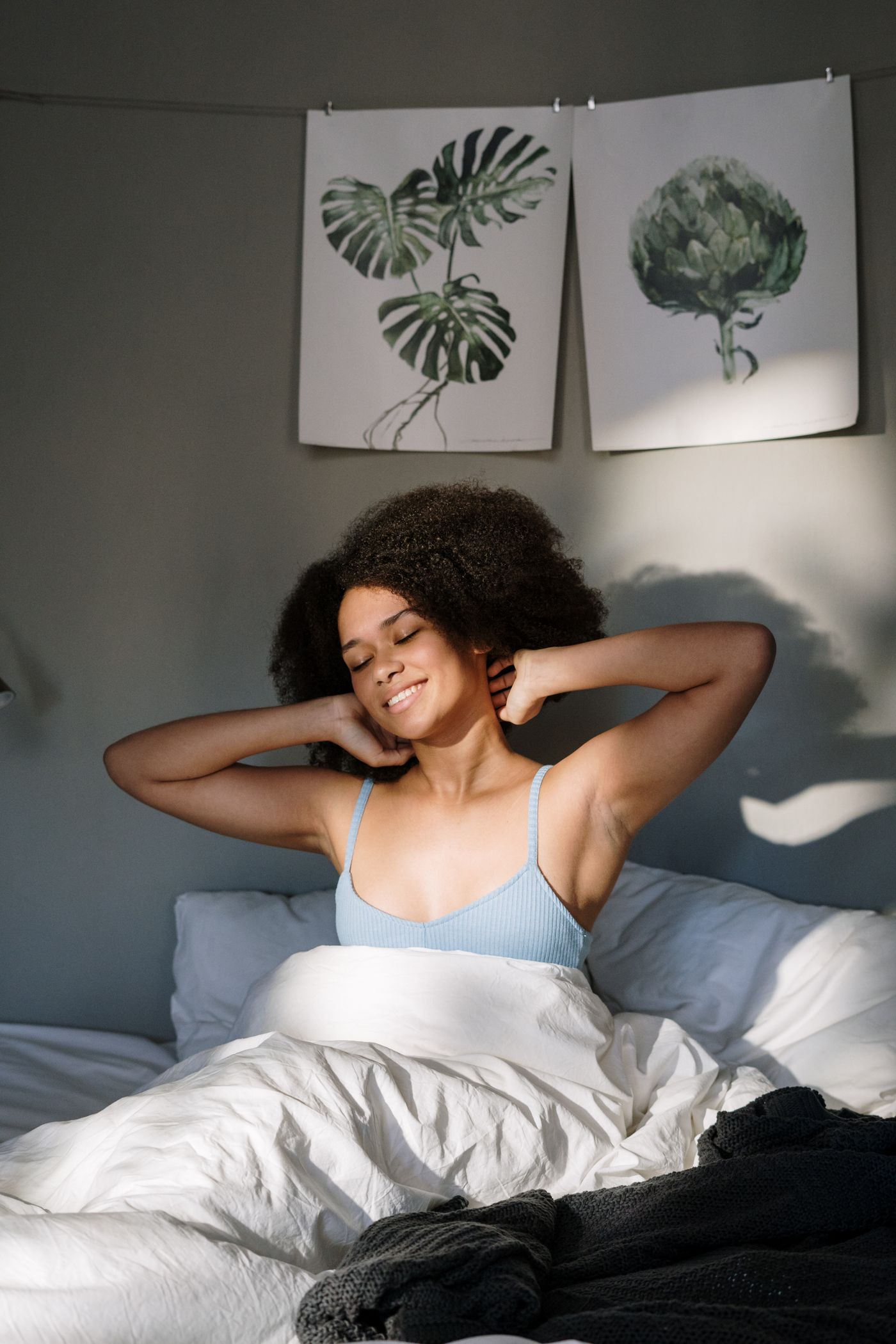 Woman stretching in a sunlit bedroom after waking