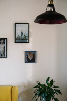 A modern cozy interior featuring wall art, a yellow armchair, and a green plant under ambient lighting.