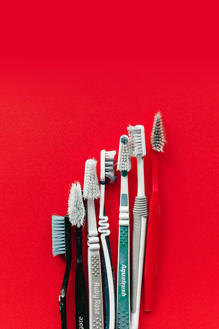 Used Toothbrushes On Red Surface