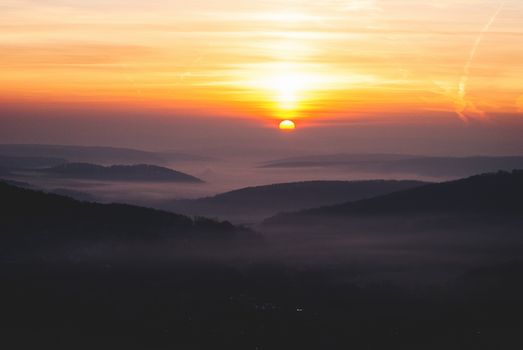 A breathtaking mountain sunrise casting warm hues over misty hills, creating a tranquil landscape.