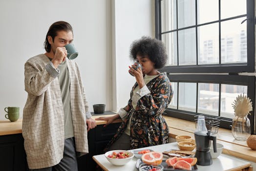 A multiethnic couple enjoys a healthy breakfast and coffee by the window, embracing their morning routine.