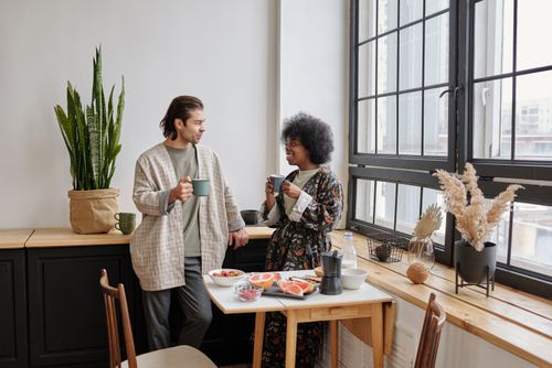 Free A joyful couple enjoys a morning coffee and healthy breakfast of grapefruit in their cozy apartment. Stock Photo