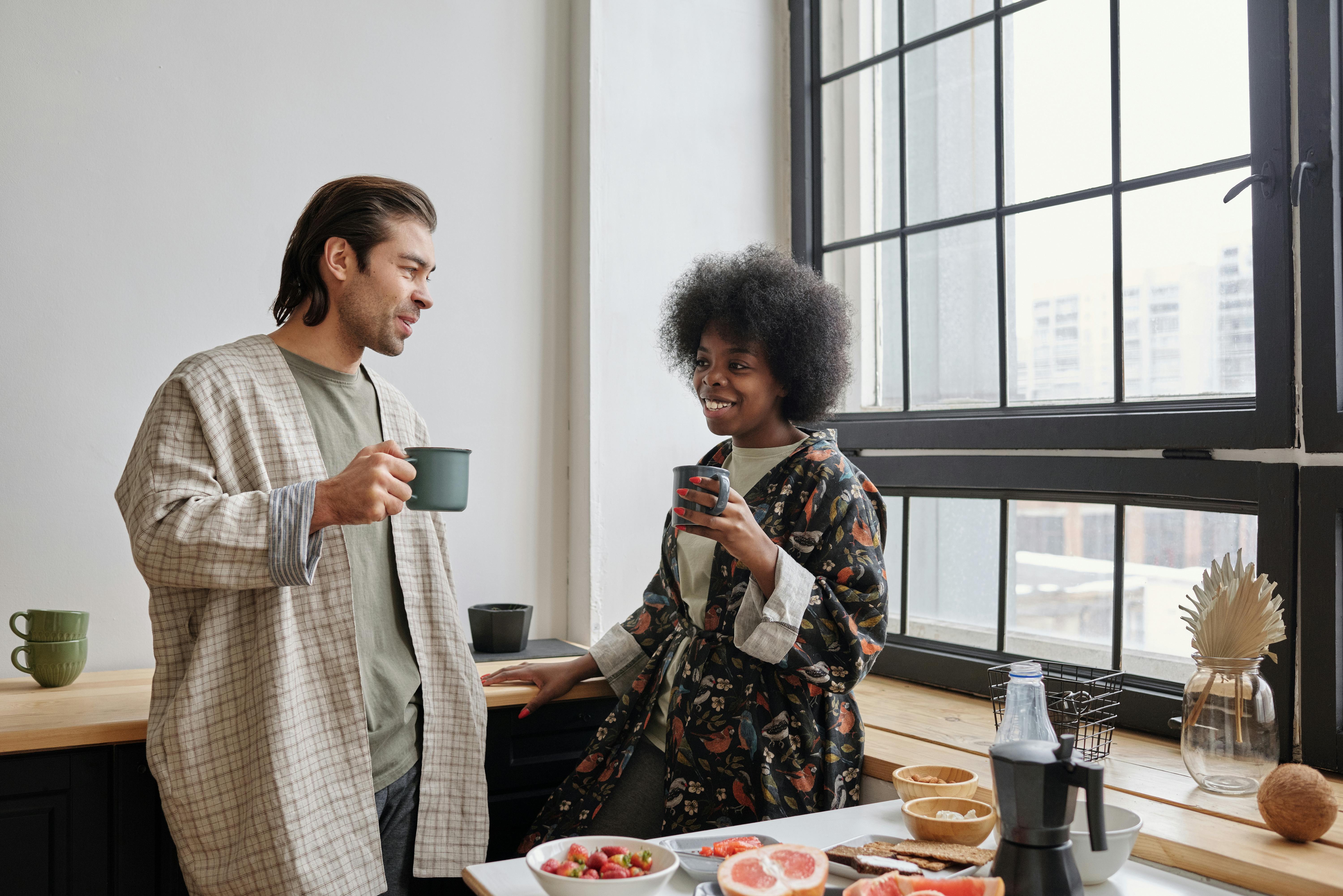 Happy couple enjoying morning coffee together in cozy kitchen setting.