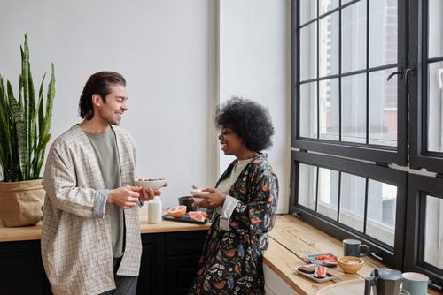 Free A happy couple shares a light breakfast by the window, showcasing togetherness and joy. Stock Photo