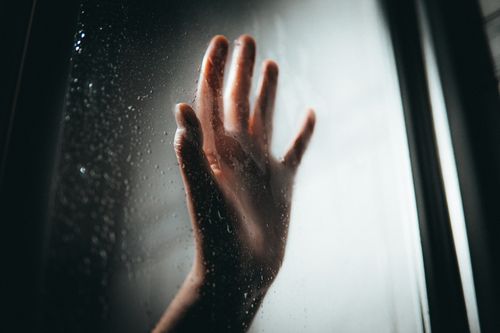 Free Close-up of a hand touching a window with raindrops, creating a moody and introspective scene. Stock Photo