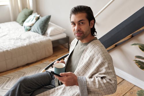 Man Sitting With a Mug and a Smartphone
