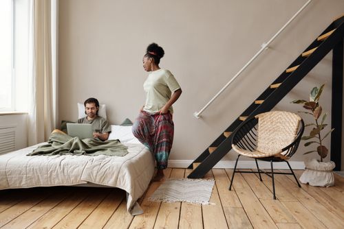 Free Couple working from home with laptops in a modern, cozy bedroom setting. Stock Photo
