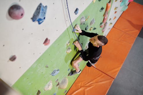 Man in Black Jacket and Black Pants Climbing On Wall