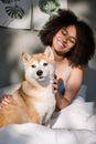 一位开朗的卷发女人和她的柴犬在舒适的卧室里，正躺在床上放松