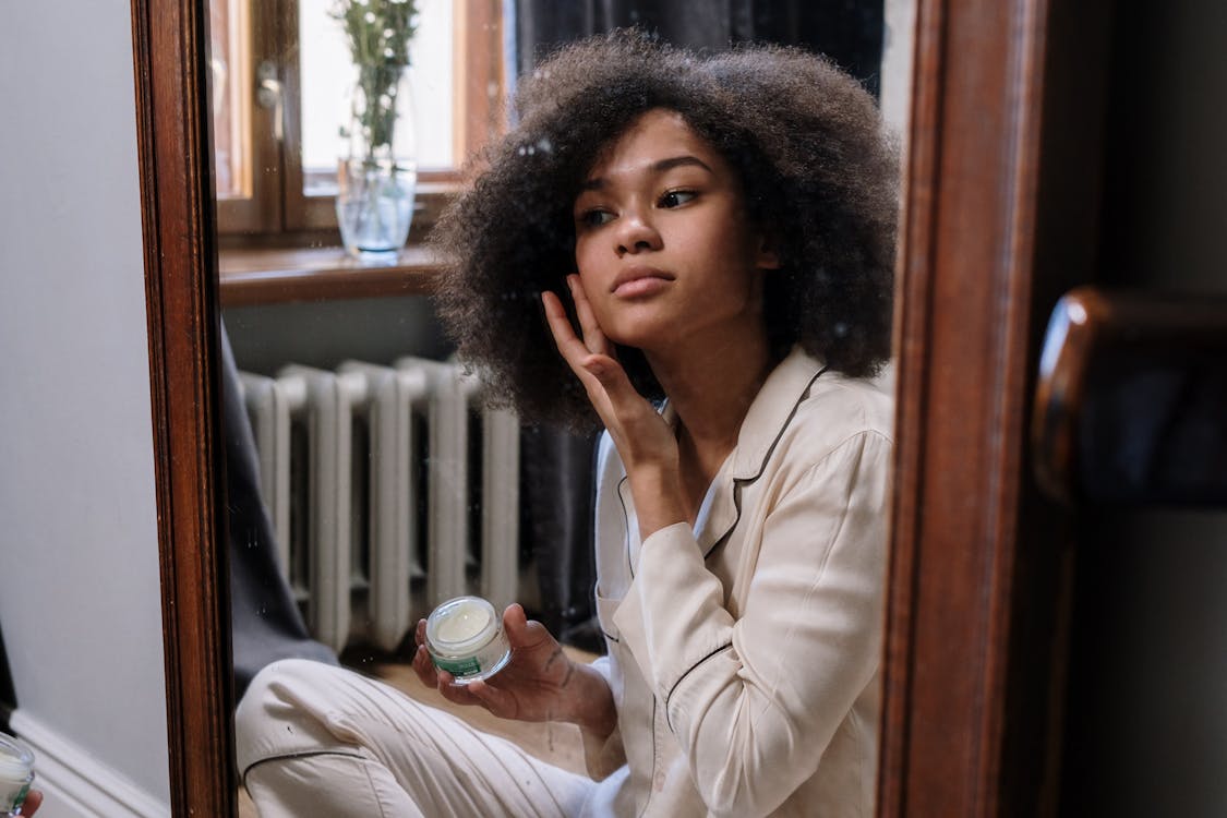  A woman looking in the mirror and applying cream