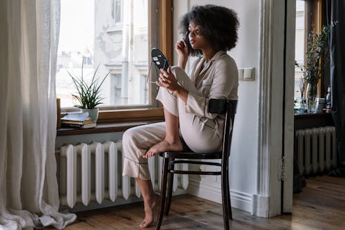 Photos gratuites de à la maison, afro, assis sur une chaise