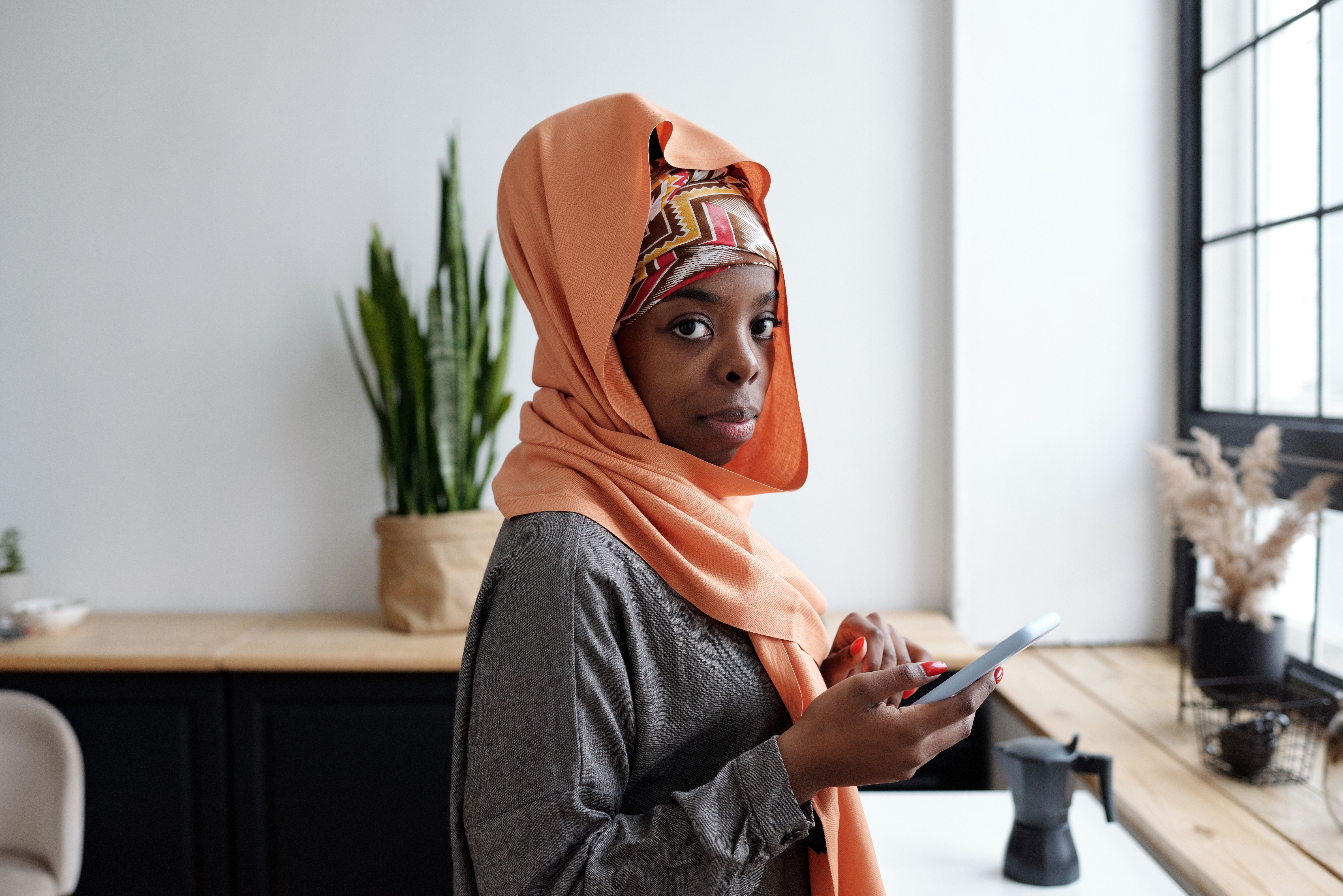 Black Muslim lady in hijab talking on phone on couch · Free Stock Photo