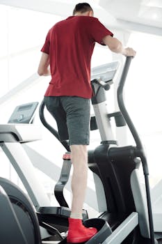 Man with prosthetic leg working out on an elliptical trainer at the gym, showcasing determination and fitness.