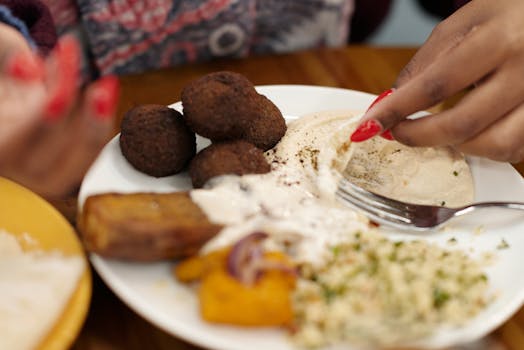 Close-up of a hand enjoying a delicious Middle Eastern falafel and hummus meal.