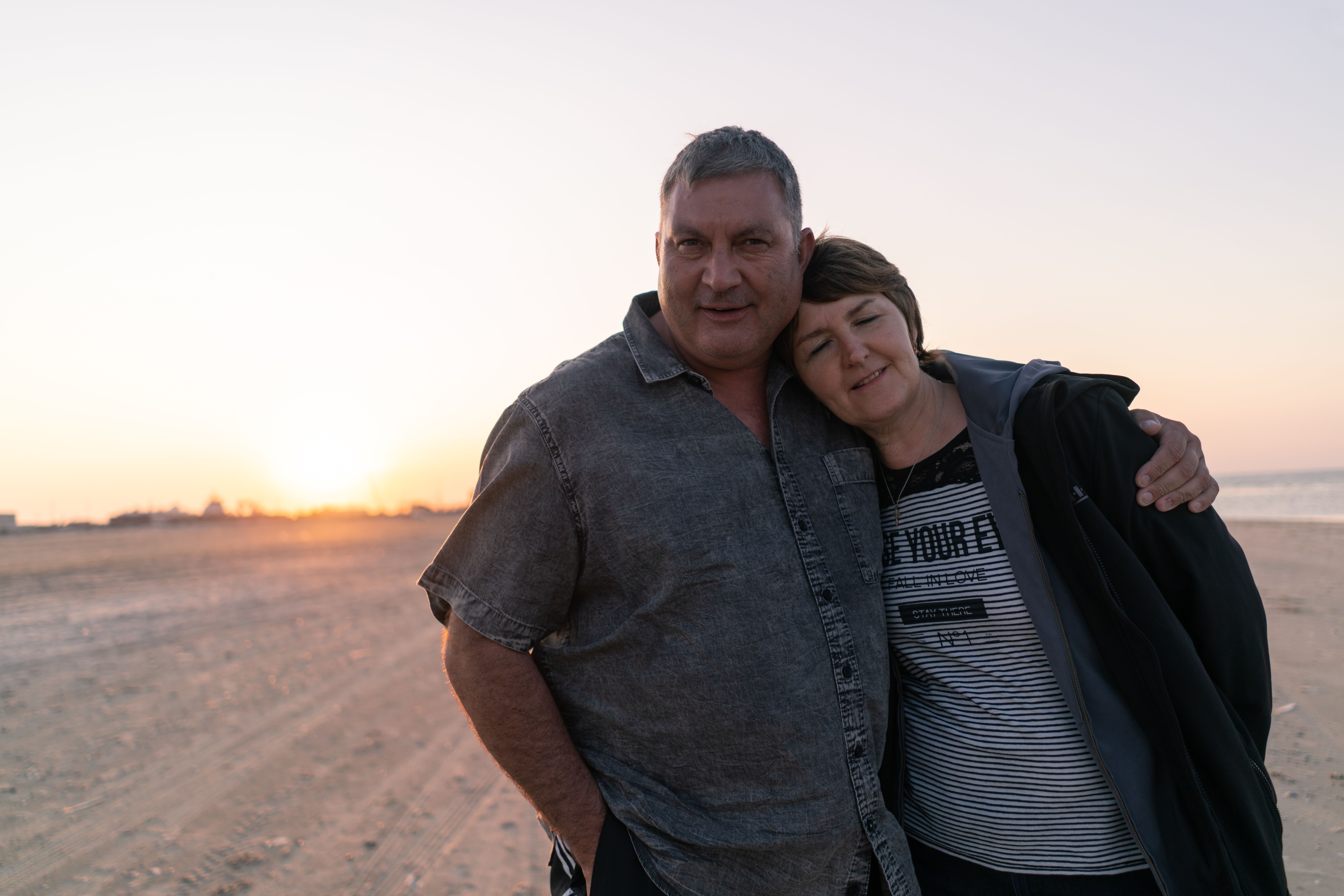 Couple Embracing on Tranquil Beach at Sunset · Free Stock Photo