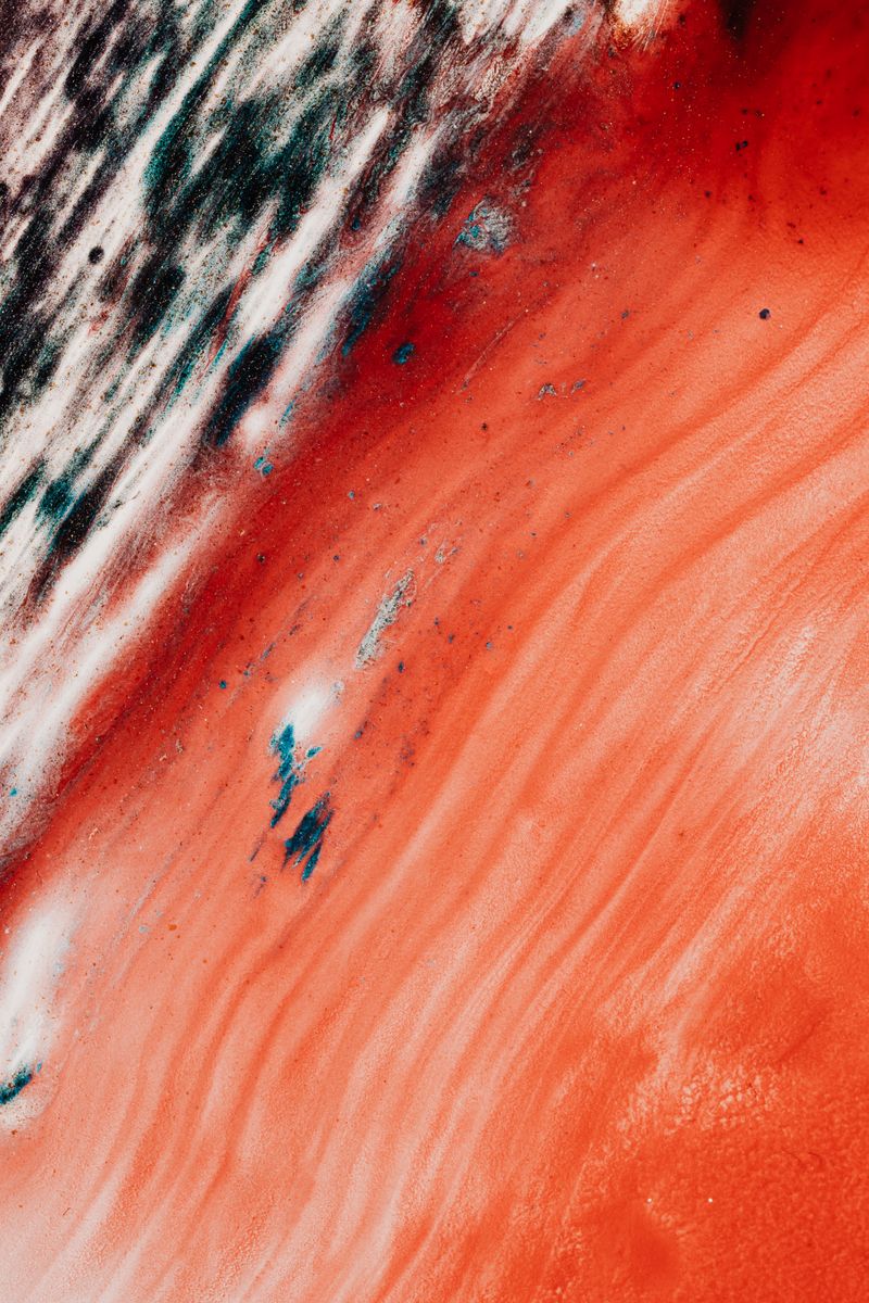 From above closeup of creative vertical fluid on vivid red surface and ink thick lines with tiny stains