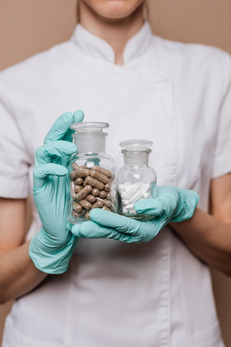 Woman Holding Two Clear Bottles With Medicines