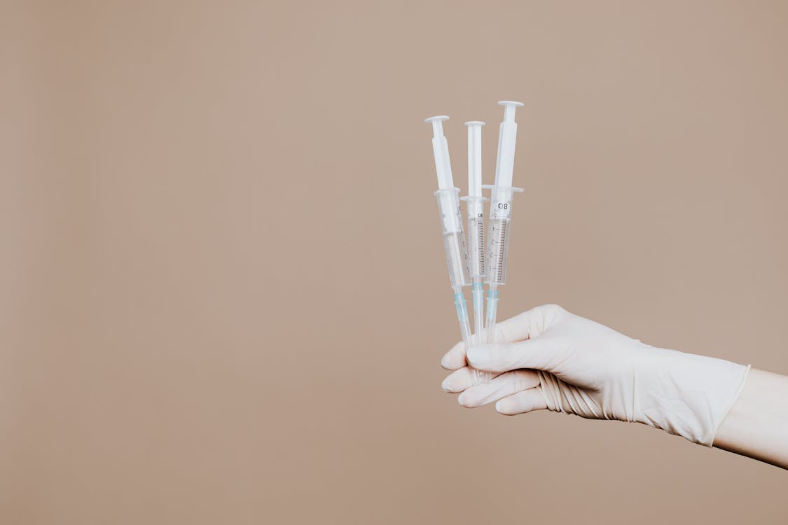 Person Holding Three Syringes with Medicine