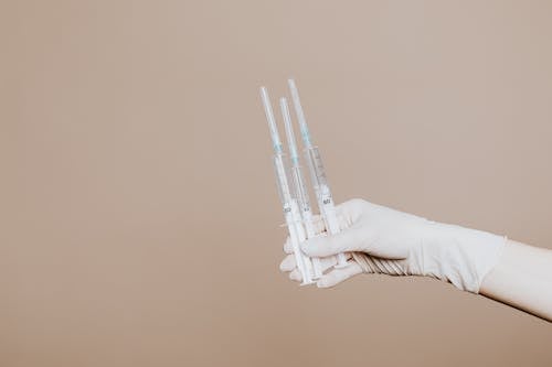 Free Person Holding Three Syringes with Medicine Stock Photo