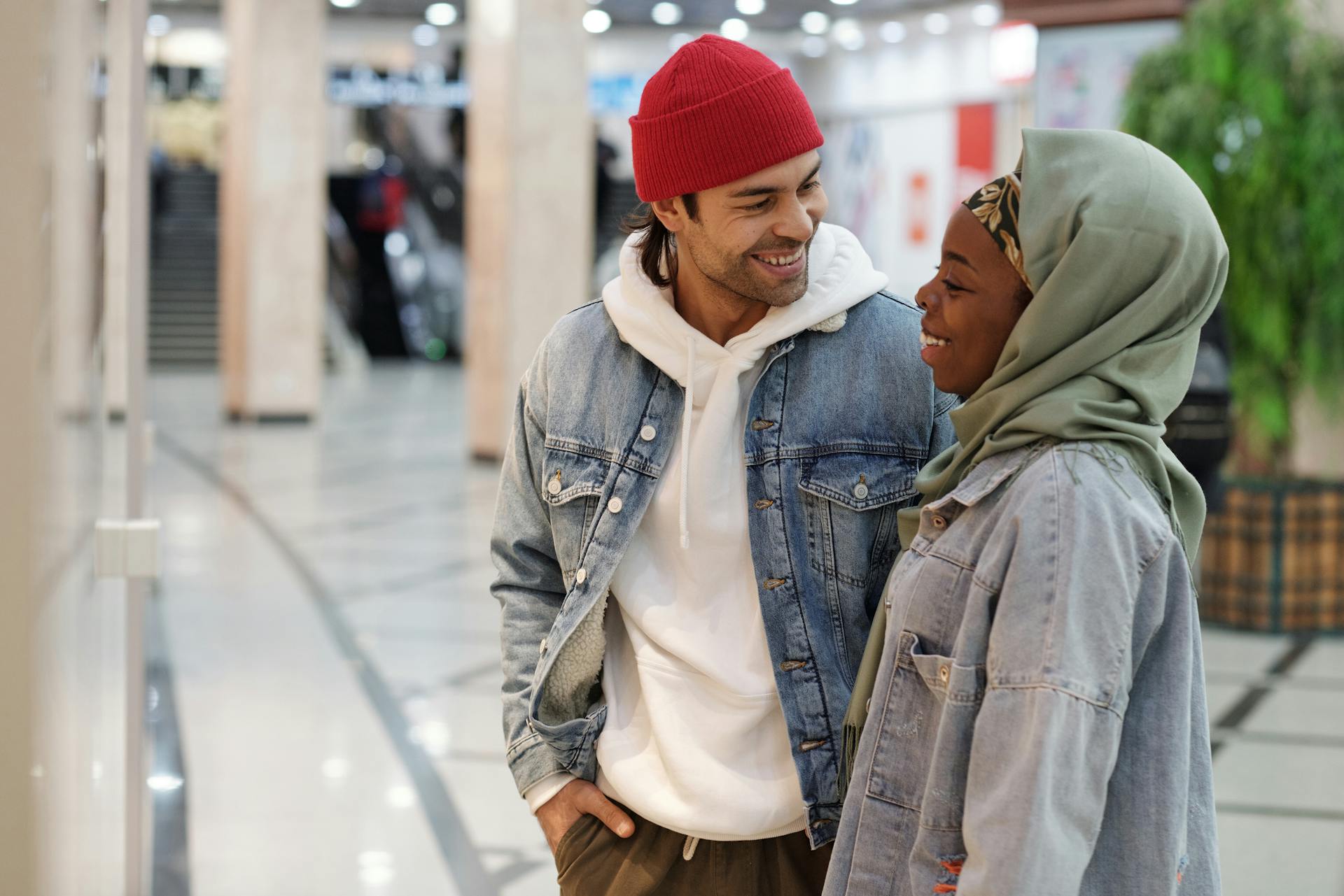 Joyful couple enjoying a shopping day in a modern mall setting, smiling and relaxed.