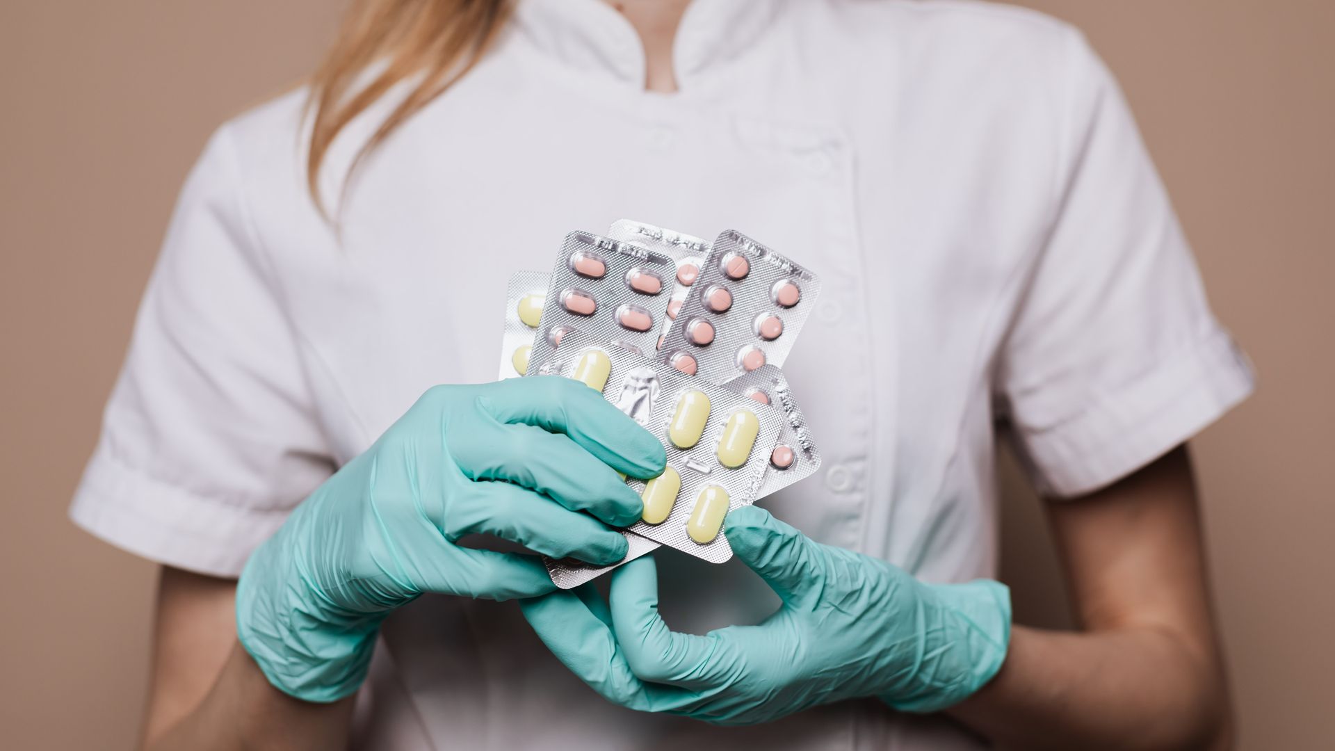 Modafinil for Night Shift Workers: Enhancing Productivity Close-up of a healthcare professional wearing gloves and holding blister packs of medication — modafinil for night shift workers