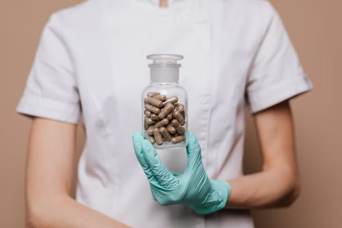 Free Person Holding Clear Bottle with Capsules Stock Photo