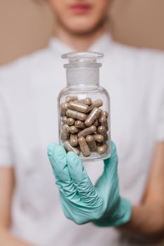 一名医护人员拿着一个装满棕色胶囊的玻璃瓶，强调临床护理的重要性