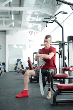 A determined man with a prosthetic leg wraps up for a workout in the gym.