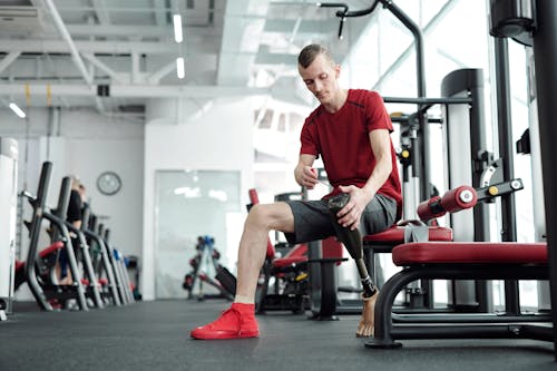 Man in Red Crew Neck T-shirt and Black Shorts Sitting on Red and Black Exercise Equipment