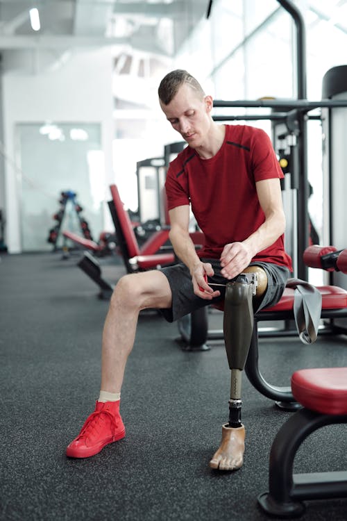 Man in Red Crew Neck T-shirt Sitting on Red and Black Exercise Equipment