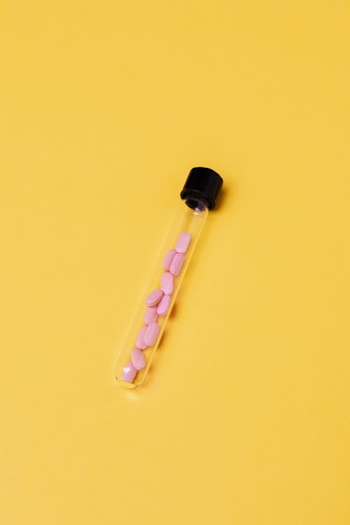Pink Capsules Inside A Glass Tube On Yellow Background