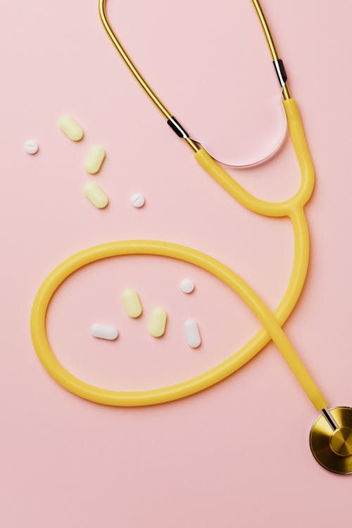Medicines And Yellow Stethoscope On Pink Background
