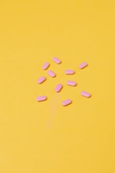粉色药片排列在鲜艳的黄色背景上，象征着健康与医学