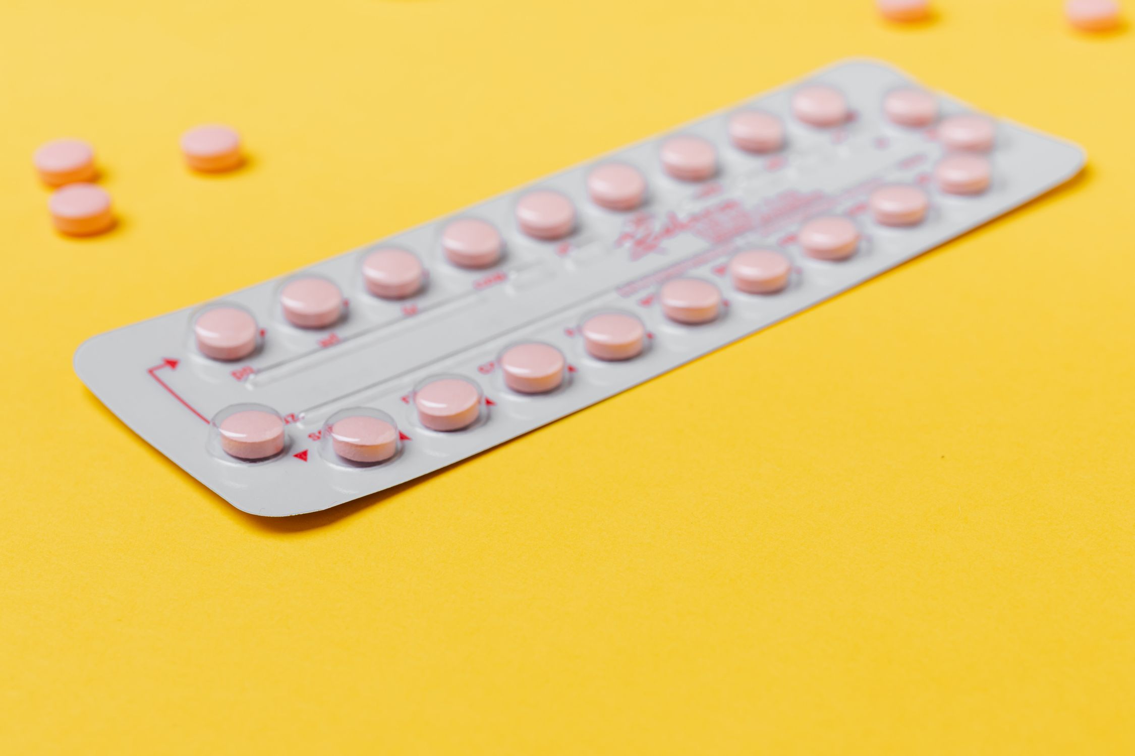 Uma cartela de pílulas anticoncepcionais em um fundo vibrante, simbolizando medicina e saúde.