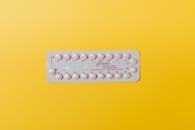 粉色药丸泡罩包装特写，置于生动的黄色背景上，代表药物概念