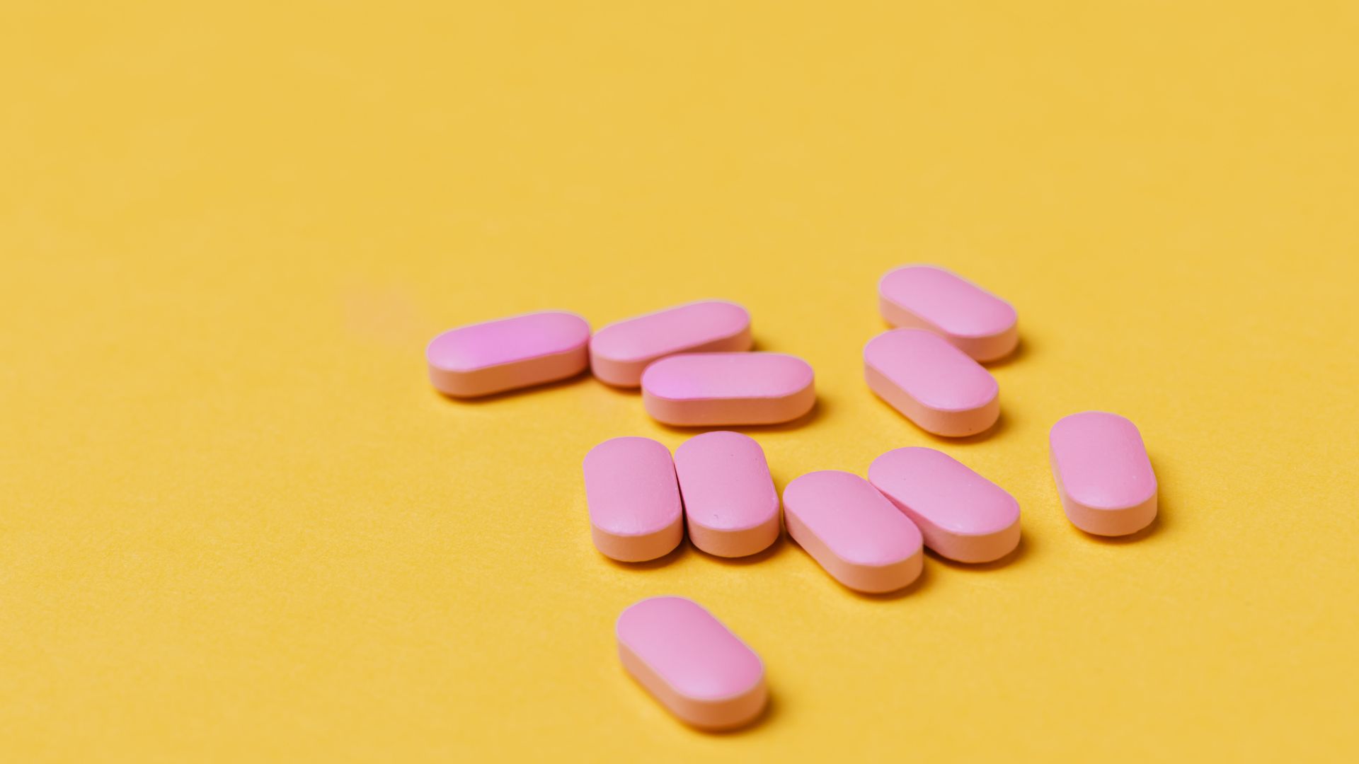 Modafinil and Liver Function: What You Need to Know Close-up of pink tablets on a vivid yellow background, perfect for medical themes — modafinil and liver function