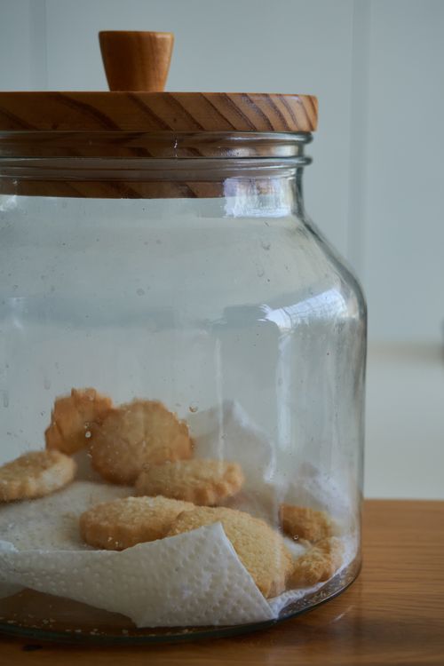 Free A close-up view of a wooden-lid glass jar partially filled with homemade cookies, creating a cozy kitchen vibe. Stock Photo