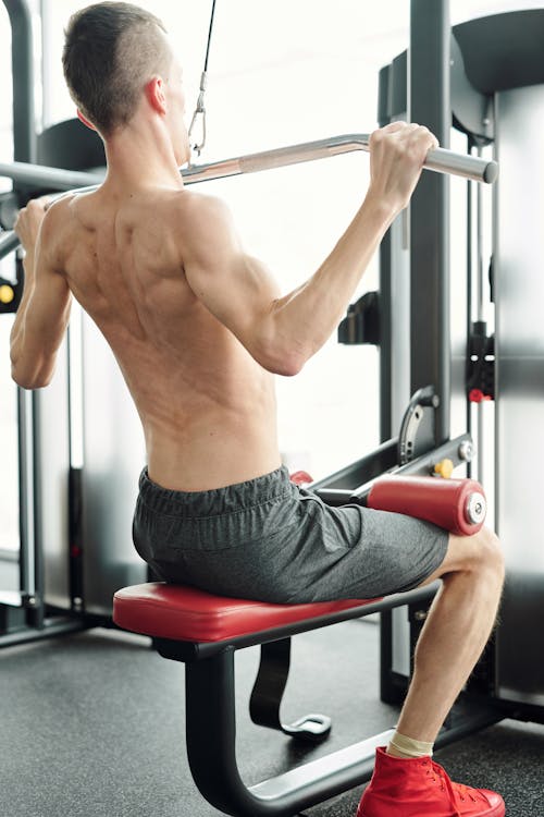 Free Shirtless Man in Gray Shorts Sitting on Exercise Equipment Stock Photo