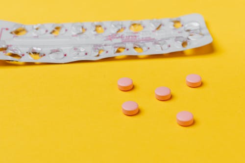 Free Pink Pills on Yellow Surface Stock Photo