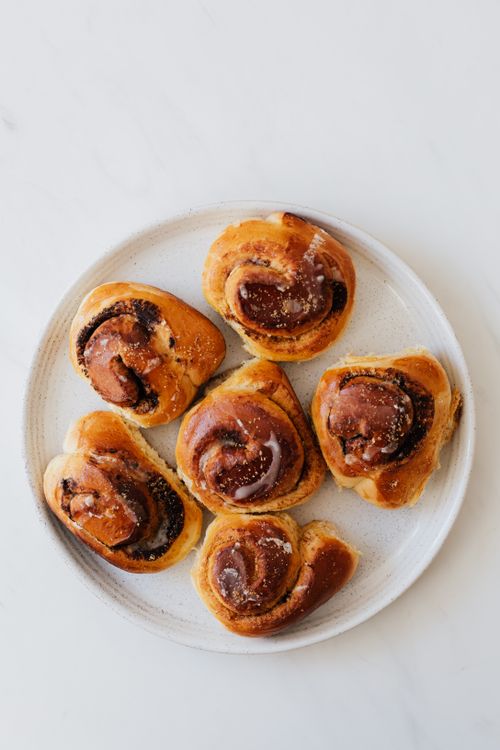Free Delicious homemade cinnamon rolls with icing on a white plate, top view. Stock Photo
