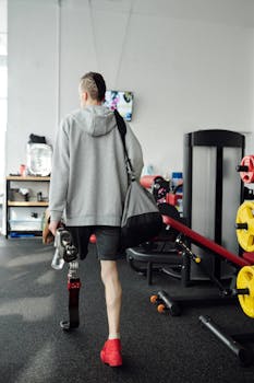 A man with a prosthetic leg carrying a gym bag walks away in a fitness center.