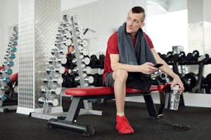 Man in Red Shirt and Black Shorts Sitting on Red and Black Chair