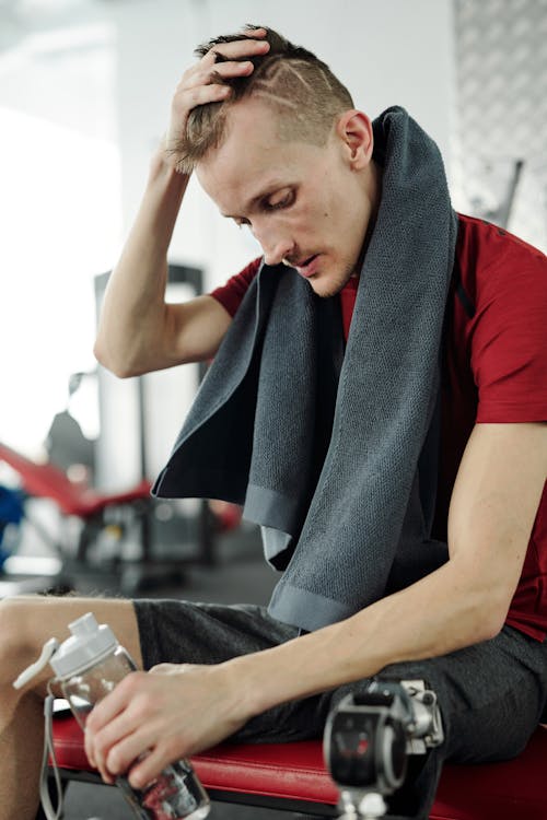 Free Man in Red T-shirt Holding Water Bottle Stock Photo