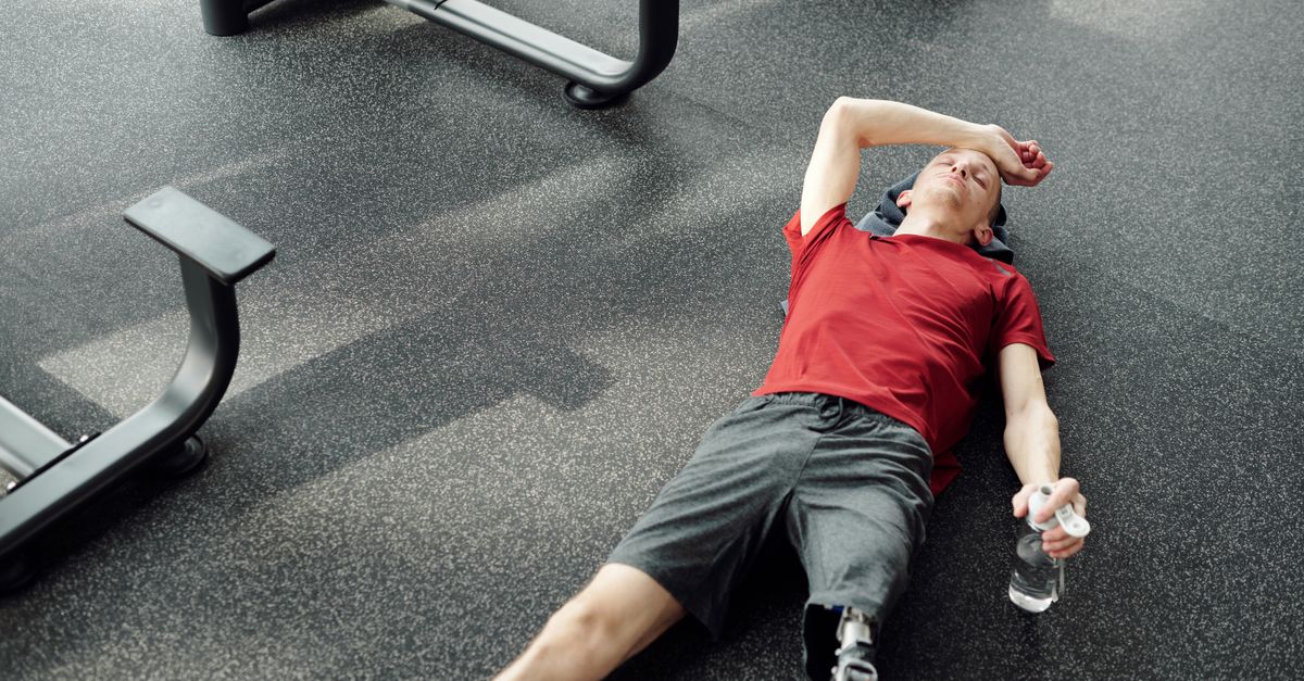 A man with a prosthetic leg rests on the gym floor, holding a water bottle after an intense workout. - Evidence evidence guide for n-acetylcysteine exercise recovery randomized trial