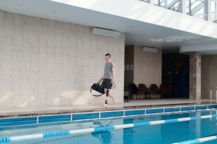 Man With Prosthetic Leg Walking By Swimming Pool