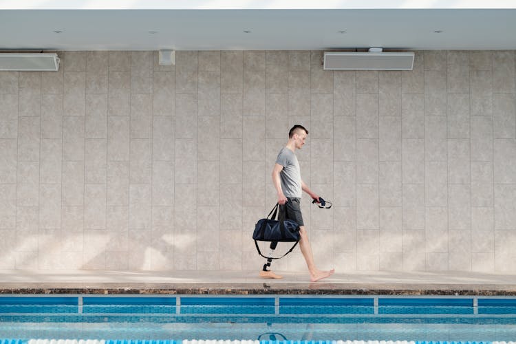 Man With Prosthetic Leg Walking By Swimming Pool