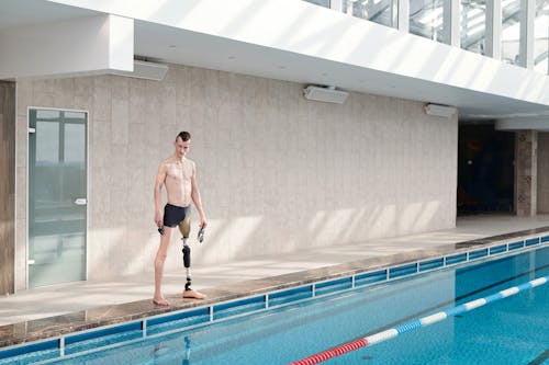 Free Man with Prosthetic Leg Standing by Swimming Pool Stock Photo
