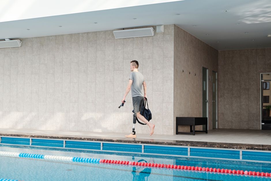 Man with prosthetic leg preparing for swimming at indoor pool.