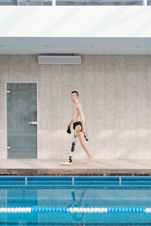 Man in Black Shorts Walking Inside Indoor Swimming Pool